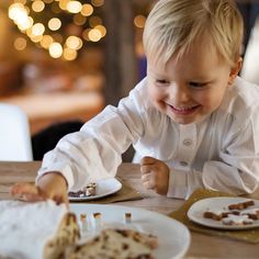 a little boy that is sitting at a table with some food in front of him