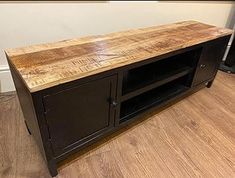 a large wooden tv stand sitting on top of a hard wood floor next to a wall