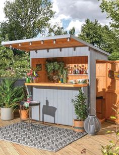 an outdoor bar with potted plants on the outside and wooden flooring in front