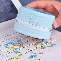 a person is using a blue and white plastic device on a laptop keyboard with confetti all over it