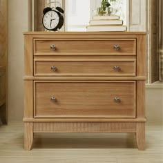 a wooden dresser sitting in front of a window with a clock on top of it