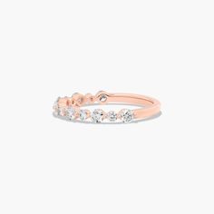 a rose gold ring with three diamonds on the top and bottom, set against a white background