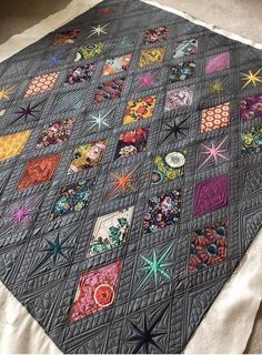 a quilt is laying on the floor with many different designs and colors, including starbursts