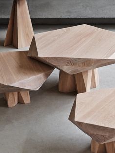 three wooden benches sitting next to each other on top of a cement floor in front of a concrete wall