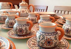 a table topped with orange and white plates covered in cups and saucers on top of each other