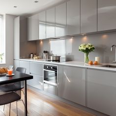 a modern kitchen with stainless steel appliances and wood flooring, along with white cabinetry