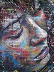 a woman's face is painted on the side of a wall with colorful graffiti