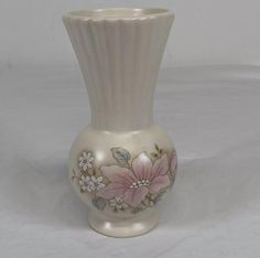 a white vase with pink flowers painted on it