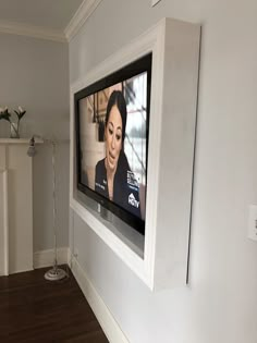 a flat screen tv mounted to the side of a wall next to a wooden floor