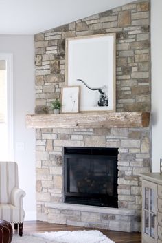 a living room with a stone fireplace and white rugs on the hardwood flooring