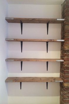 three wooden shelves with black metal brackets on each shelf and brick wall in the background