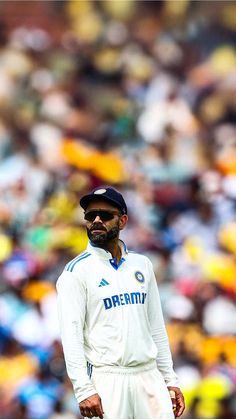 a man standing in front of a crowd wearing a white shirt and blue cap with the number twenty on it