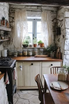 a kitchen with an oven, table and chairs next to a window in the wall