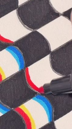 a person is drawing with colored pencils on a black and white checkered paper