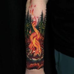 a man's arm with a fire in the forest tattoo on his left forearm