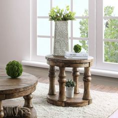 a wooden table sitting in front of a window next to a potted plant on top of a rug