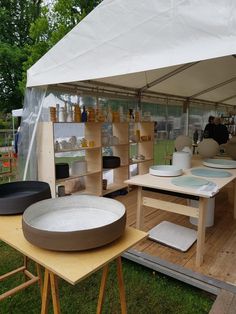 an outdoor area with tables, chairs and pots on the ground in front of a tent