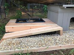 a cat house built into the side of a chicken coop with gravel and rocks around it