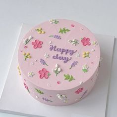 a pink birthday cake with flowers and the words happy day on it's side