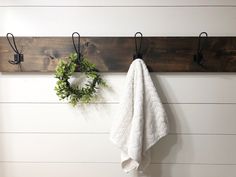 a towel hanging on a wall next to a wreath and two hooks with clothes hangers