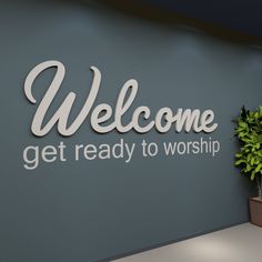 a welcome sign is on the wall next to a potted plant