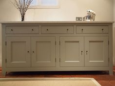 a sideboard with two vases sitting on top of it next to a rug