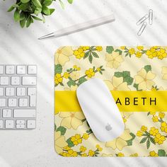 a computer mouse and keyboard sitting on top of a yellow flowered mouse pad with the name abeth