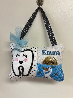 a toothbrush holder hanging on the wall with an emma pillow attached to it