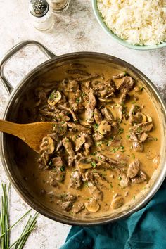 beef and mushroom stew in a pan with rice on the side