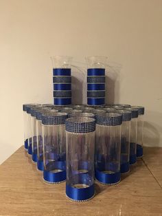 six clear cups with blue rims are stacked on top of each other in front of a white wall