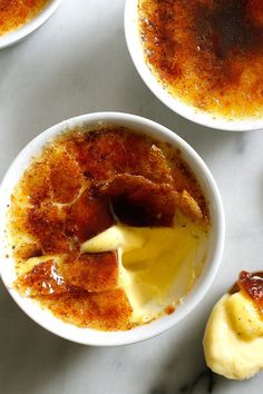 three bowls filled with food sitting on top of a white marble counter topped with sauce