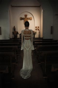 the back of a woman in a white dress standing in front of pews at a church