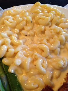 macaroni and cheese is on top of asparagus in a white plate