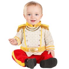 a baby sitting on the ground wearing a costume and smiling at the camera with his hands in his pockets