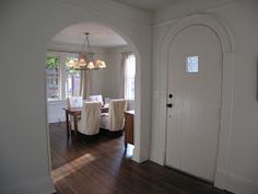 an archway leads to the dining room and living room in this house with hardwood floors