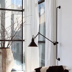 a living room with a couch, lamp and vase on the window sill in front of it