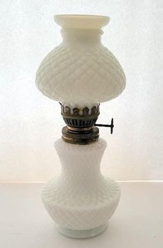 a white vase sitting on top of a table next to a light fixture with a black cord