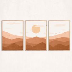 three paintings hanging on the wall in front of a white wall, each with an orange sunset