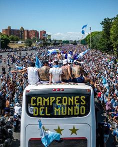 a group of people sitting on top of a white bus in front of a crowd