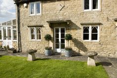 a stone house with two large planters in front of it and windows on the side