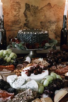 a table topped with lots of cheese and crackers next to two wine bottles filled with candles