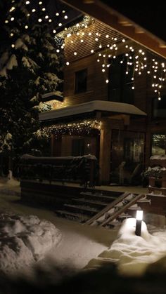 a house covered in snow at night with christmas lights