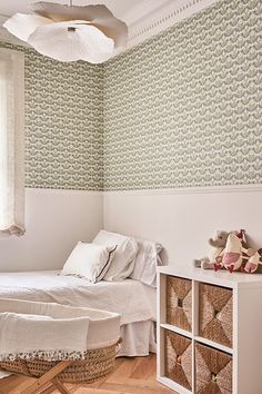 a white bed sitting next to a window in a room with green wallpaper and wooden floors