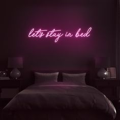 a bed with a purple neon sign above it that says life is beautiful on the wall