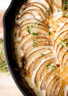 a pan filled with potatoes covered in gravy and garnished with parsley