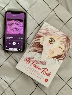 a cell phone sitting on top of a bed next to a book titled after her ride