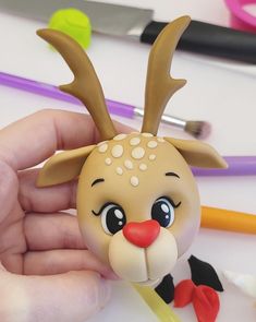 a hand holding a plastic toy with a deer on it's head and eyes