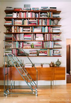 a bookshelf filled with lots of books next to a stair case