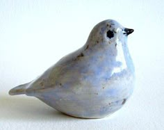 a ceramic bird sitting on top of a white table