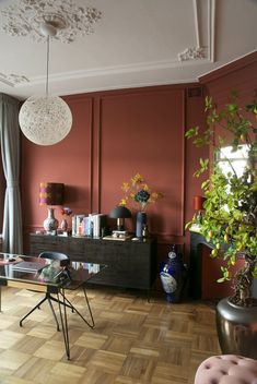 a living room filled with furniture and a plant on top of a hard wood floor